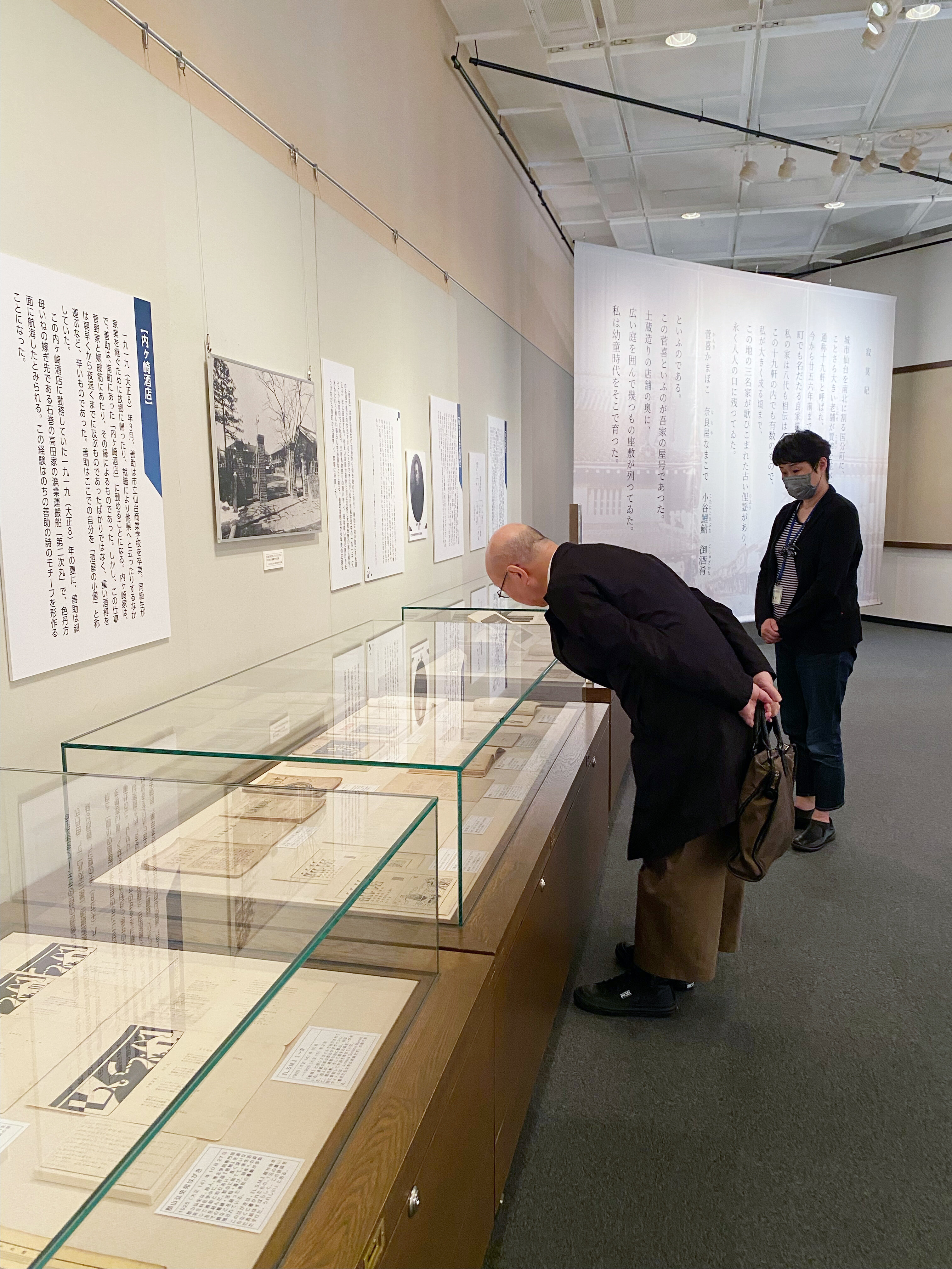 ガラスケースの中の資料を熱心に読む鷲田館長.jpg