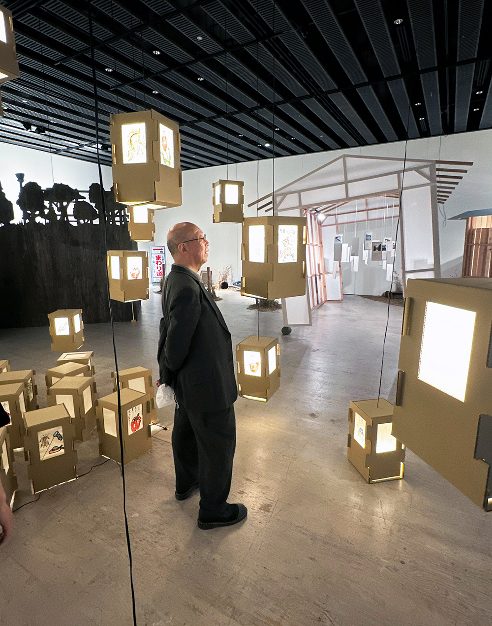 8.会場内の「灯籠」の展示を見上げる鷲田館長.png